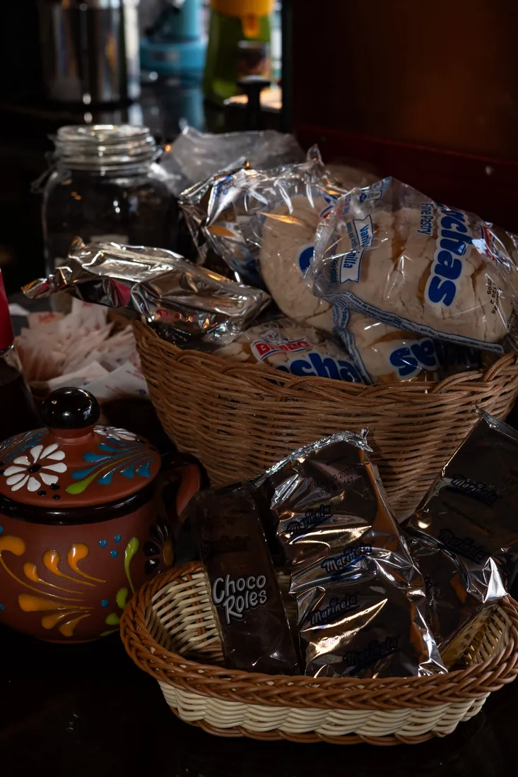 A basket of conchas and Choco Roles beside a hand-painted clay jar