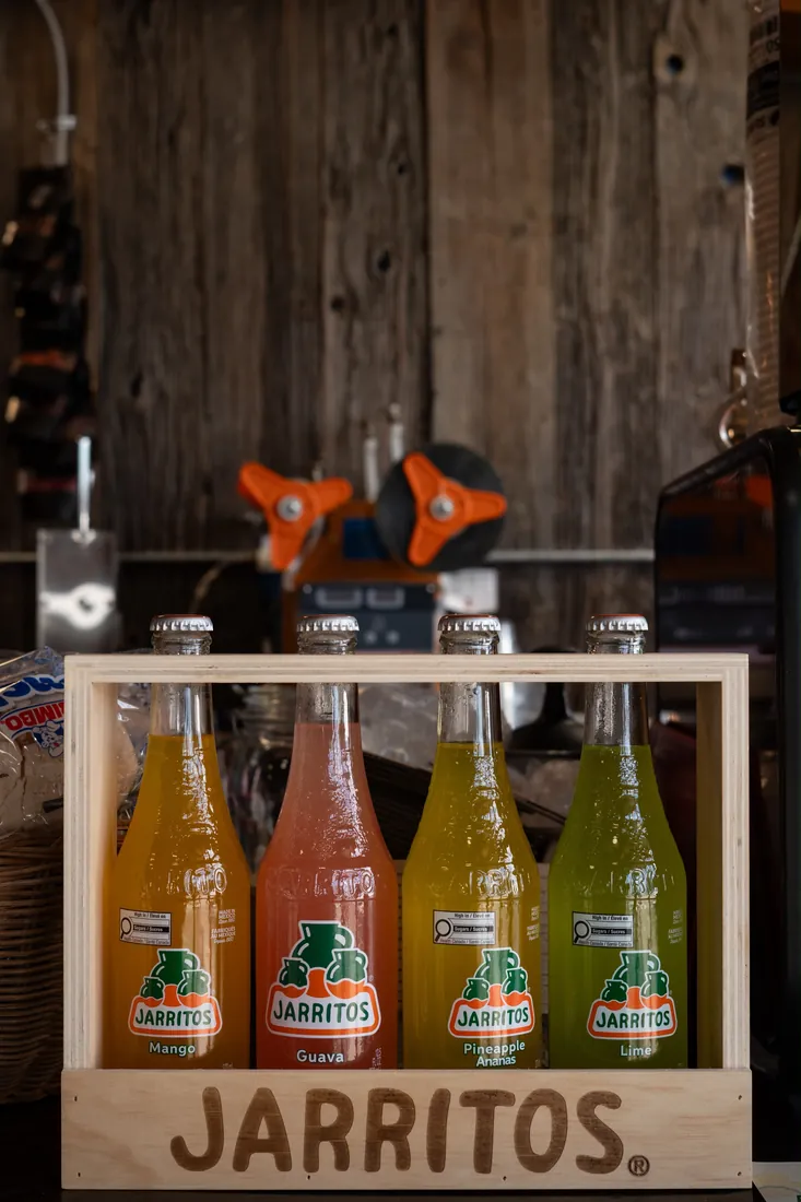 Mango, guava, pineapple and lime Jarritos in a wooden Jarritos crate