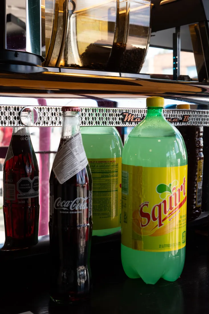 Glass-bottle Mexican Coca-Cola and a two-litre Squirt beneath the café's espresso machine and coffee grinder